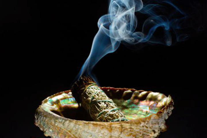 An image of sage burning in a shell dish